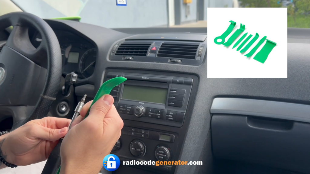 Hand using a green plastic prying tool to remove the dashboard trim around a Skoda Octavia radio unit.