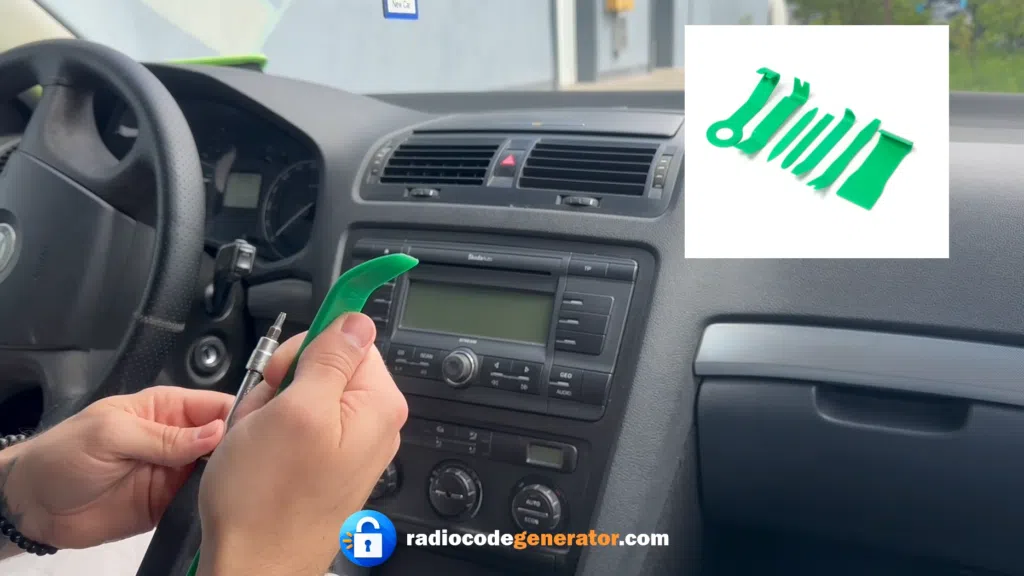 Hand using a green plastic prying tool to remove the dashboard trim around a Skoda Octavia radio unit.